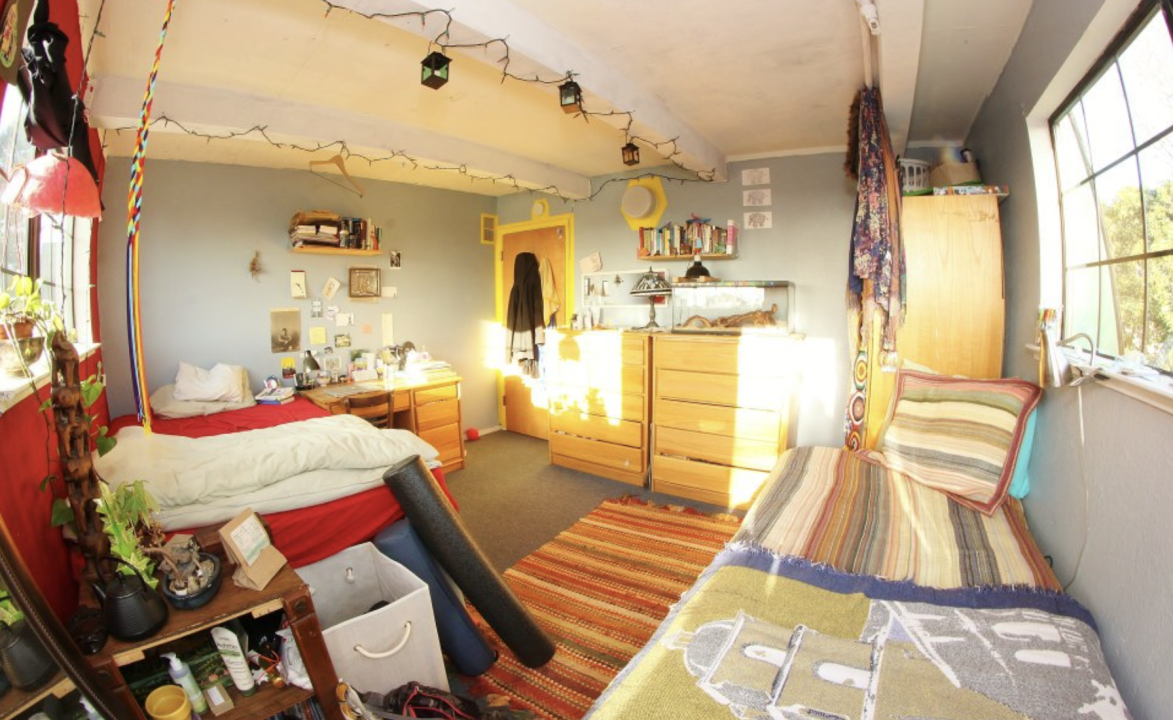 Double Room in a Co-op.A shared bedroom with two beds, personal decor, and string lights. The warm lighting and eclectic furnishings create a welcoming, homey space.